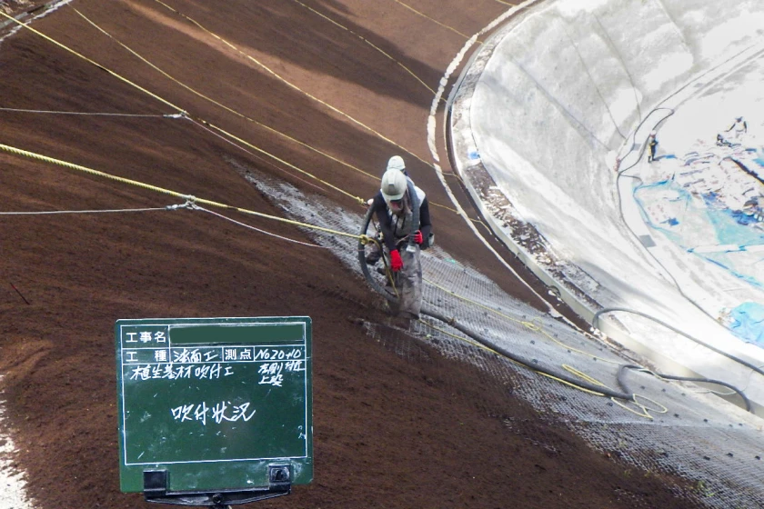 急斜面でロープを使って作業する法面工事作業員