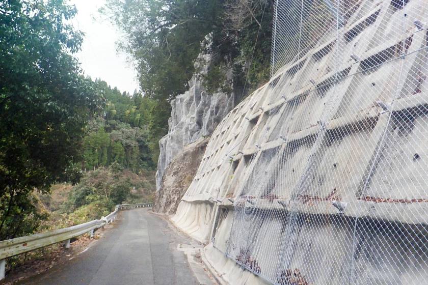 コンクリートで補強された斜面に落石防止ネットを設置した現場