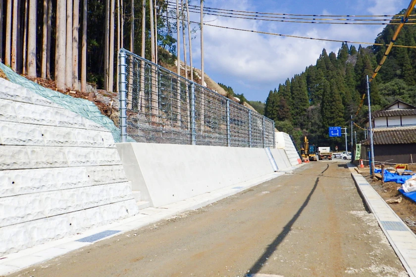 落石防止柵と擁壁が設置された山間道路の工事現場
